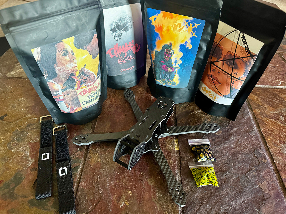 Flat lay of the ILLmatic 5" freestyle FPV frame kit by DamagD, featuring custom-branded packaging with street art designs, carbon fiber drone frame, LiPo straps, and hardware packs. A complete beginner-friendly, bargain freestyle setup that rivals top-tier frames like Apex, Flipmode, TANQ, Syncmode, and Vannystyle.