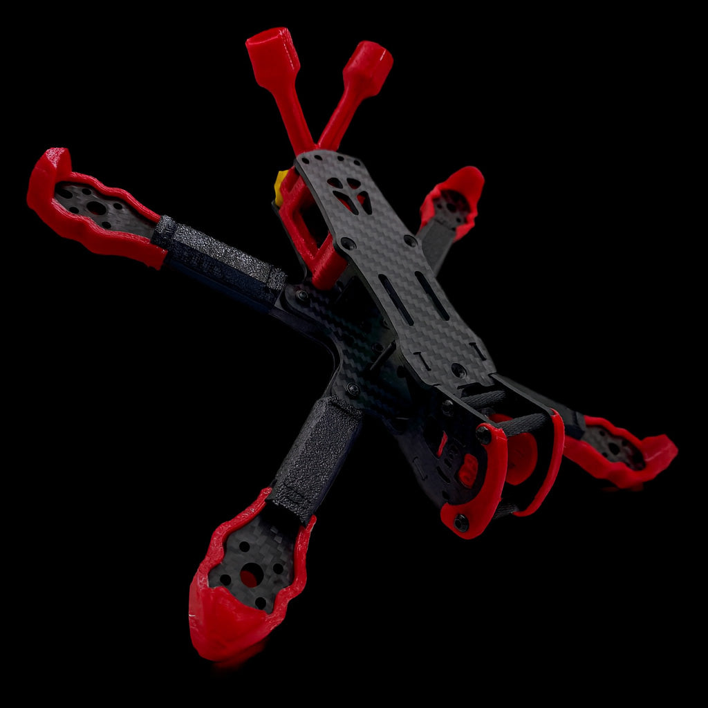 Angled rear view of the ILLmatic FPV frame with Shredpool 3D printed red TPU bumpers, skids, and antenna mounts — a high-visibility accessory kit for freestyle builds