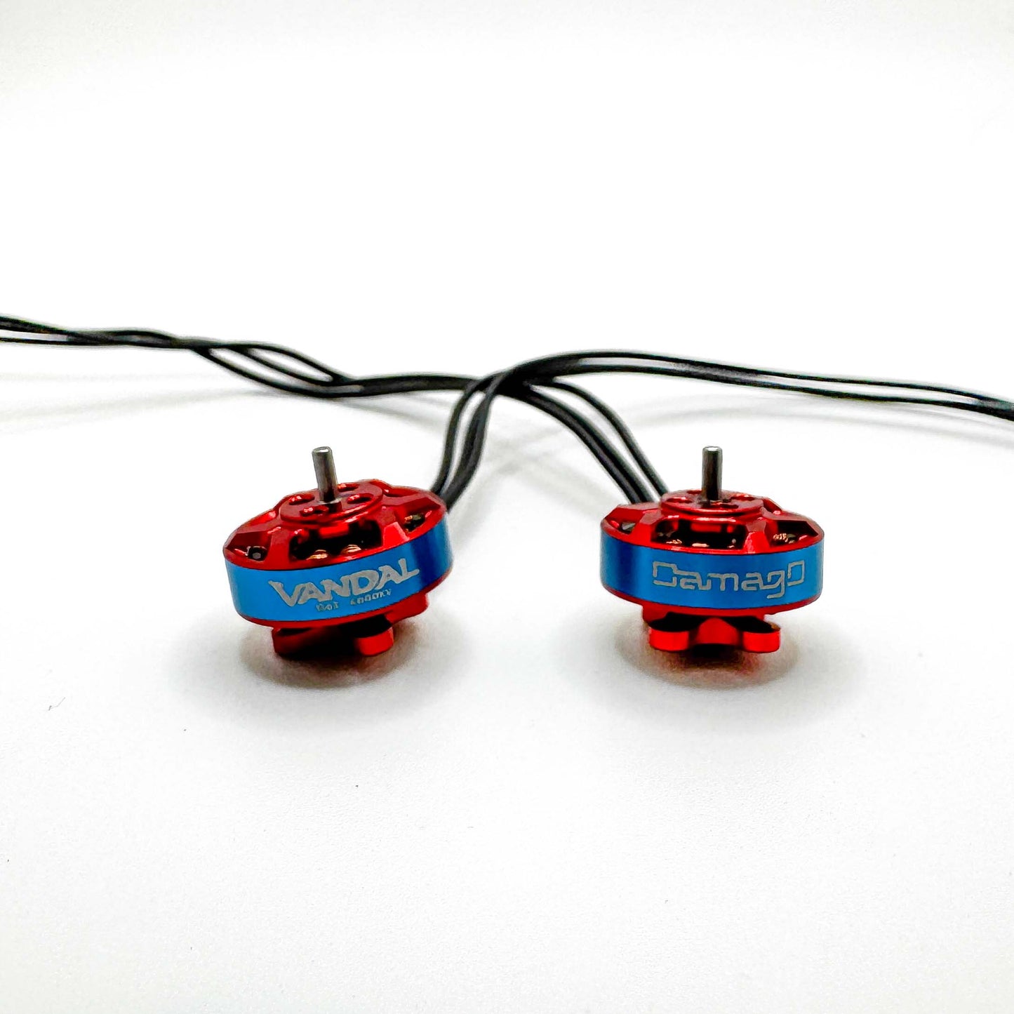 Close-up of DamagD Vandal 1303 6000KV FPV motors in red and blue, optimized for 4S micro quads; comparable to RCINPOWER and Caddx 1303 for sub-250g freestyle and cinematic flying.